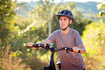 Young cyclist riding a mountain bike through a scenic dirt road on a sunny day. A peaceful outdoor...