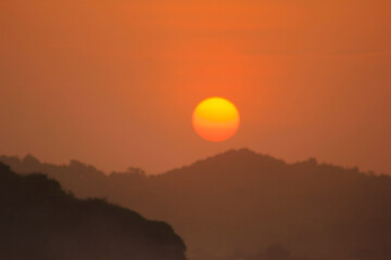 orange sunset photo with the sillhouette of hill