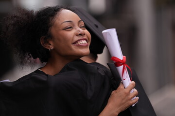 Two graduates in caps and gowns beam with joy, embracing and cheering in celebration. Their wide...