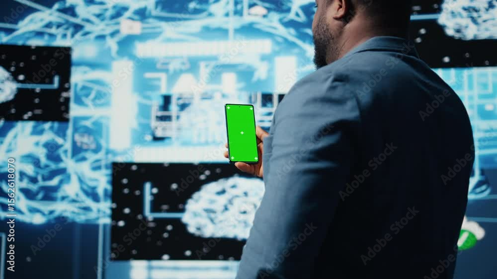 Poster focused black it professional looks at phone with green screen, standing in a digital artificial int