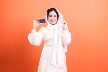 Cheerful Muslim Woman Holding Credit Card: Secure Online Shopping. The image showcases a confident...