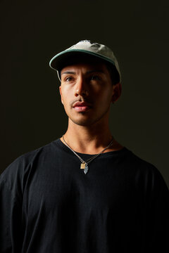 Young man in casual attire poses under dramatic lighting