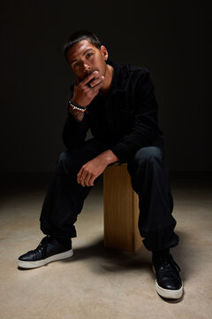 Stylish young man posing confidently in a dark studio setting