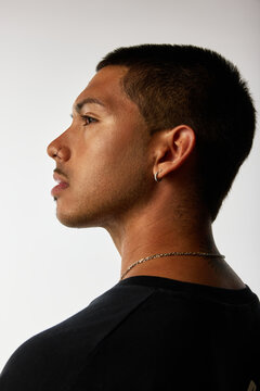 Profile view of a young man with modern hairstyle and jewelry