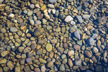 Fondo de piedras de arroyo con aguas cristalinas, piedras redondas