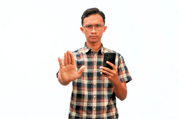 An Asian man holding a smartphone and showing a stop gesture.