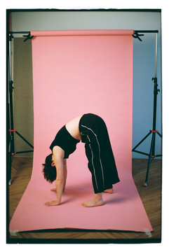 Stretching in studio with pink backdrop 