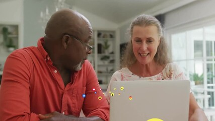 Senior couple checking social feed via laptop screen starting floating reaction emojis across frame - Powered by Adobe