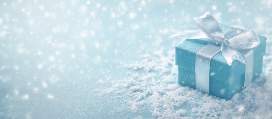Blue gift box with shiny white ribbon resting on snowy surface, surrounded by falling snowflakes and soft winter light, symbolizing holiday season, Christmas celebration, and festive giving