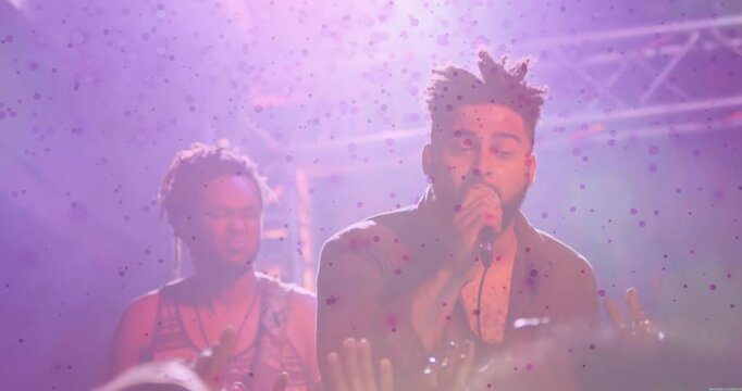 Concert singer entering purple light gripping microphone singing as confetti falling and drumming