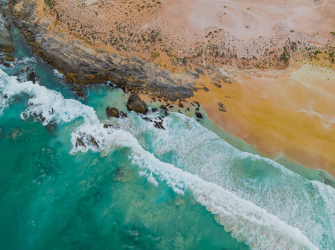 Waves breaking onto sandy beach and rocky outcrop