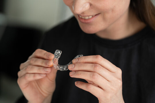 Smiling Person Holding Clear Dental Aligner