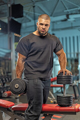 male athlete stands confidently in a gym, lifting weights with focused determination His muscular...