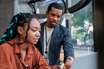 Mentoring: Father helps daughter with laptop work.