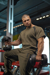 male athlete focuses intently while lifting dumbbells in a well equipped gym The setting features...