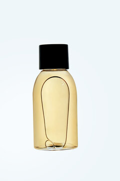 Clear bottle with orange shampoo or shower gel on a light background