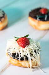 Mini donuts with chocolate and strawberry toppings, captured in a low angle macro shot
