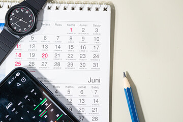Desk calendar with pencil, marker, and smartphone displaying digital calendar
