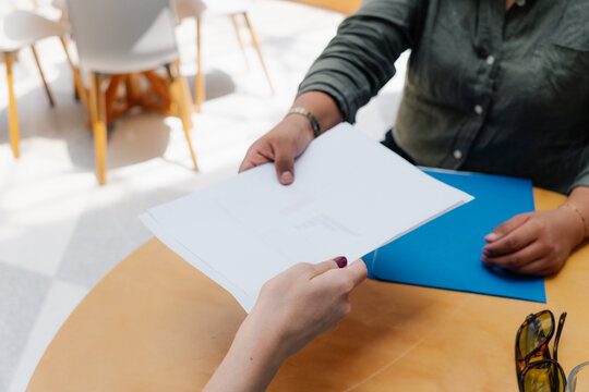 Businesswoman handing her colleague a document.