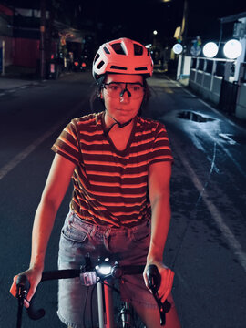 Woman on a bicycle at night under red lights