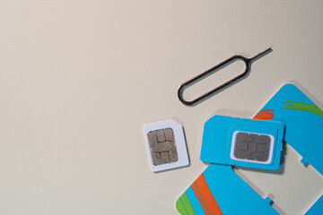 New SIM card popped out from its thin plastic frame, leaving an empty slot. Mini SIM and SIM tray lie beside it