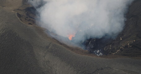 White smoke and lava are coming out of a volcano crater, captured from above by a drone, showcasing the raw power and geothermal activity of nature. Amazing nature travel background