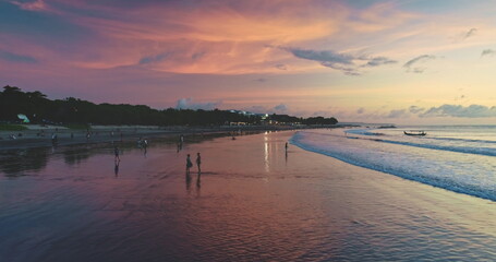 Dreamland Beach in Bali, Indonesia, offers a breathtaking view during sunset, with tourists enjoying the colorful sky and calm ocean waves, creating a serene and picturesque scene