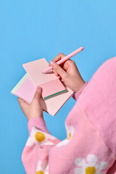 Someone is writing on a pink notepad with a matching pink pen