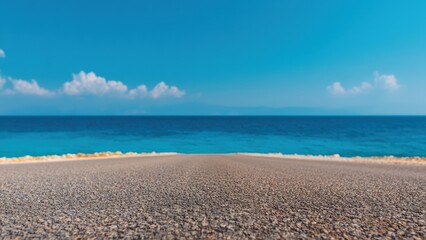 Fototapeta premium Scenic view of an empty asphalt road leading towards the vast blue sea under a serene cloudy sky, creating a tranquil and inviting coastal landscape
