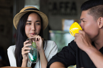 Smiling couple using laptop and drinking coffee in cozy cafe. Captures modern lifestyle, relationship, and remote work culture.