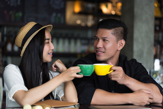 Smiling couple using laptop and drinking coffee in cozy cafe. Captures modern lifestyle, relationship, and remote work culture.