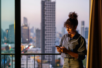 Woman at home on balcony using phone