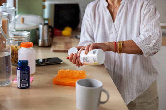 Woman filling pill organizer in kitchen