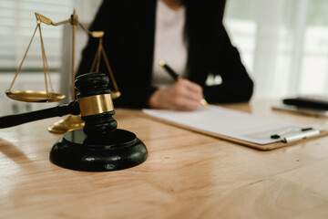 Two professionals are signing a legal agreement at a desk, with a judge’s gavel nearby. The scene reflects law, business contracts, and formal documentation.x