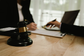 Two professionals are signing a legal agreement at a desk, with a judge’s gavel nearby. The scene reflects law, business contracts, and formal documentation.x