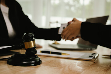 Two professionals are signing a legal agreement at a desk, with a judge’s gavel nearby. The scene reflects law, business contracts, and formal documentation.x