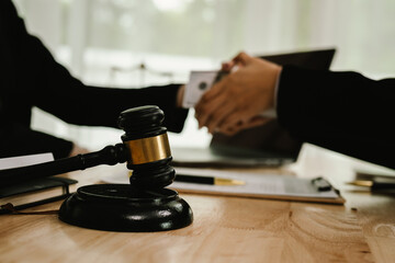 Two professionals are signing a legal agreement at a desk, with a judge’s gavel nearby. The scene reflects law, business contracts, and formal documentation.x