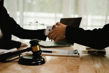 Two professionals are signing a legal agreement at a desk, with a judge’s gavel nearby. The scene...