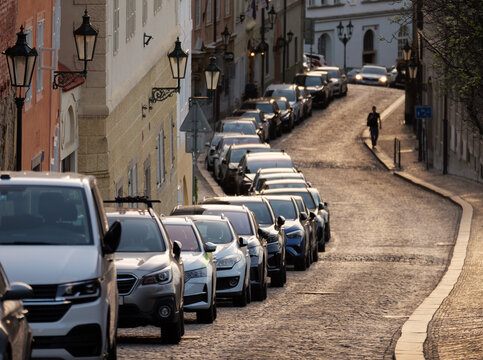 A line of cars parked on a cobblestoned street