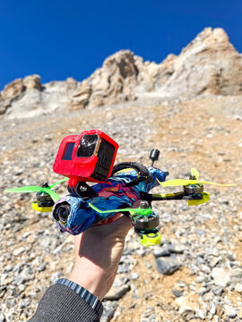 Crashed FPV drone held by hand in rocky mountains