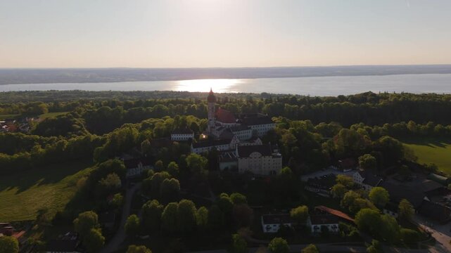 Drone footage of Kloster Andechs on Holy Mountain in Upper Bavaria, Germany. View of monastery, baroque church, lake Ammersee and green countryside near Munich at golden hour. Luftbild Heilige Berg. 