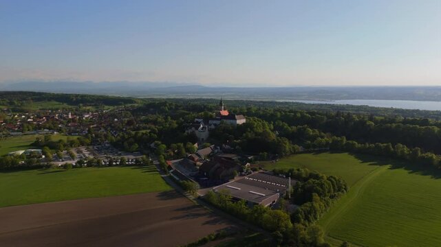 Luftaufnahme Kloster Andechs bei Muuenchen, Bayern. Drohnenvideo Wallfahrtskirche auf dem Heiligen Berg am Ammersee mit Landschaft, See und Sonnenuntergang. Burg Andechs. Braustuberl des Klosters. 
