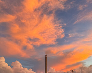 Dramatic fiery clouds against a deep blue sky at sunset or sunrise, creating a breathtaking natural...