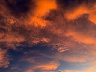 Dramatic fiery clouds against a deep blue sky at sunset or sunrise, creating a breathtaking natural...