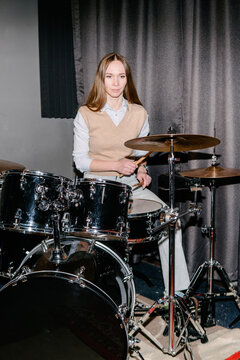 A young woman plays the drums.