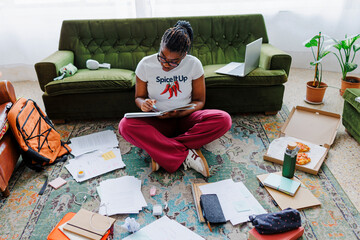 Student studying at home surrounded by books and notes