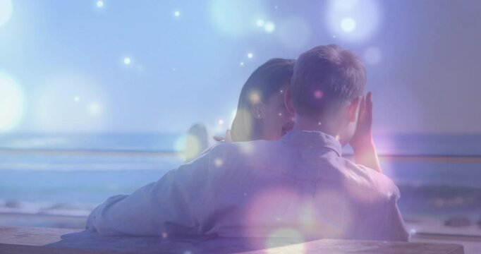 Woman laughing at glowing orbs triggers man cupping cheek, embracing, sharing moment for marketing