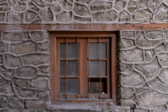 Fototapeta Rustic wooden window framed by patterned stone wall in Ladakh, India