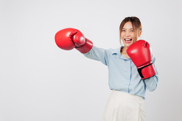 Boxing energy and boxing punch shown by fit Asian young business woman in red gloves. Strong smile and fighter pose reveal her power and kickboxing spirit. isolated studio white background