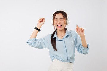 Happy young Asian woman listening music and raising hands with joy, dancing to beat while music energizes her lifestyle and uplifts her emotional state. isolated studio white background